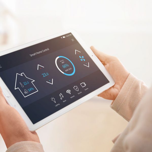 Modern home control app with flat interface on tablet display. Woman holding tablet. Sun light in background. Close-up.